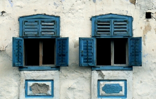 Two open windows in the wall of an old building