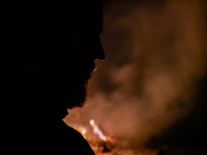 Silhouette of a man's face against a smoky fire