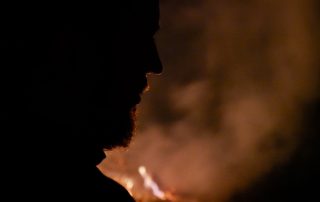 Silhouette of a man's face against a smoky fire