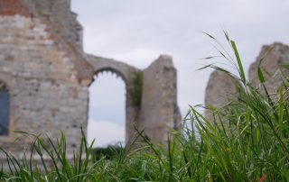 The side of a partially-ruined church in Norfolk, UK, with the horizon visible beyond an empty window