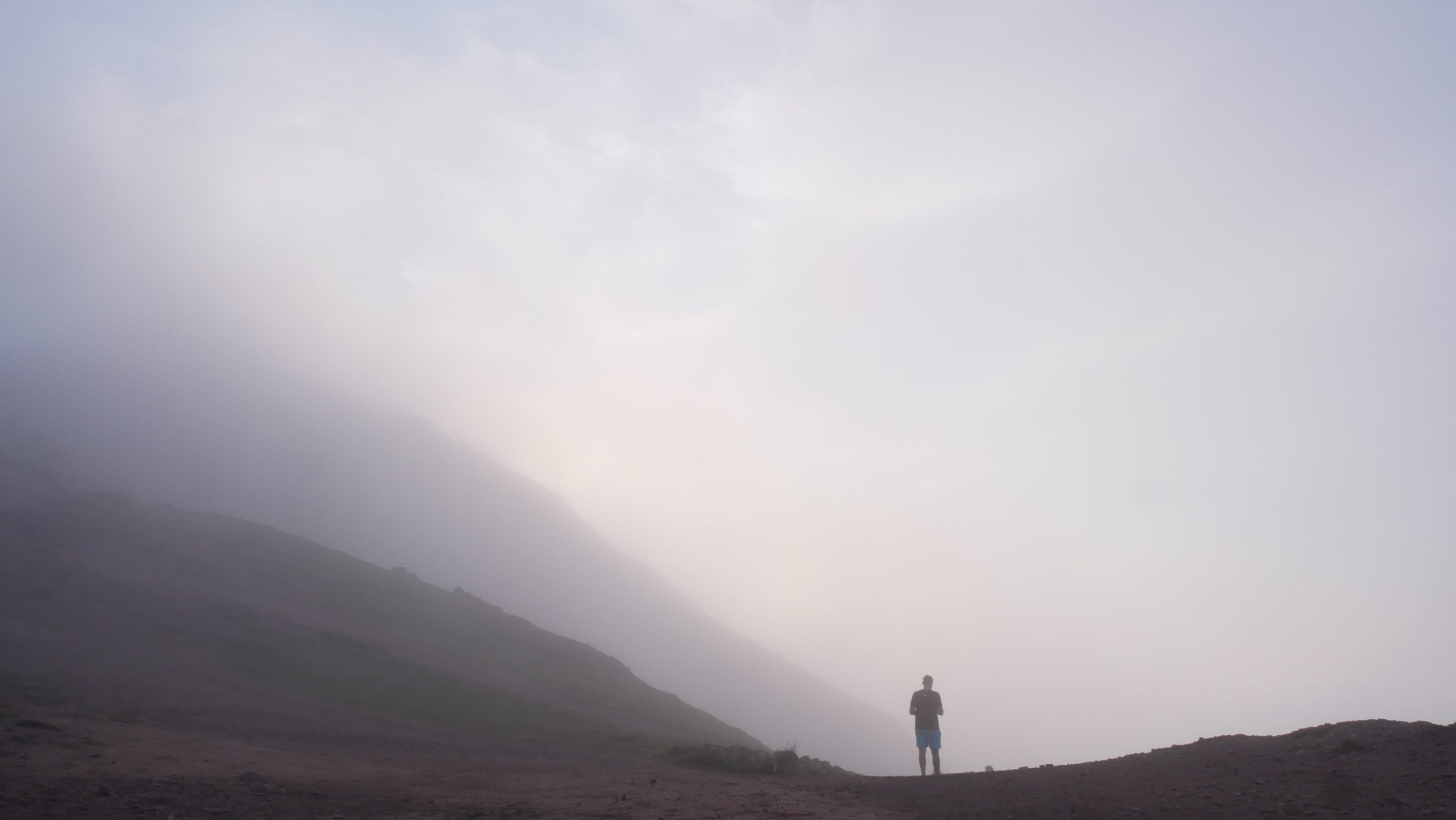 A person silhouetted in the mist at the top of a mountain